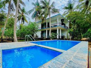 a villa with a swimming pool in front of a house at Eagle Wilpattu Resort in Wilpattu