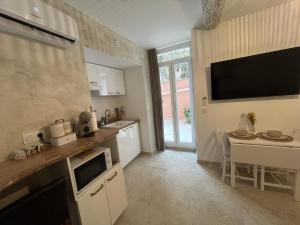 a kitchen with a table and a tv on the wall at Cocon de Nuit - appartement RDC, avec terrasse in Orange