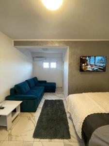 a living room with a blue couch and a bed at Stan na dan Pecinci in Pećinci