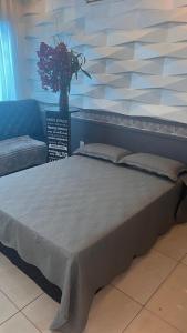 a large bed in a room with a vase of flowers at Flat Luz in Guarabira