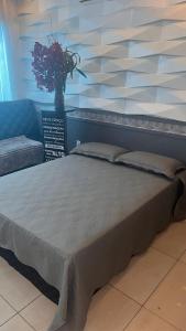 a large bed in a room with a vase of flowers at Flat Luz in Guarabira