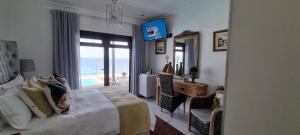 a bedroom with a bed and a desk and a window at Dolphin Wave in Mossel Bay