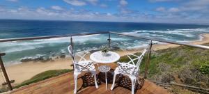 a balcony with a table and chairs and the ocean at Dolphin Wave in Mossel Bay