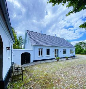 a white house with a bench in front of it at Farmhouse in idyllic settings in Ærøskøbing