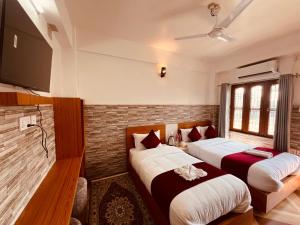 a bedroom with two beds and a flat screen tv at Hotel Kandara in Pokhara