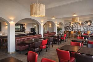 a restaurant with tables and chairs and a bar at The Originals City, Hôtel Les Bruyères, Dax Nord in Castets