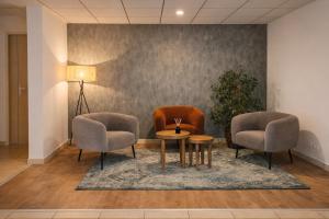 two chairs and a table in a waiting room at The Originals City, Hôtel Les Bruyères, Dax Nord in Castets