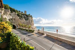 a road next to the ocean with a castle on the cliff at SEAHORSEROOM - Frontemare con Idromassaggio in Finale Ligure