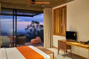a bedroom with a bed and a desk and a window at Wishing Tree Boutique Resort and Spa - Haputale's Panoramic Hideaway in Haputale