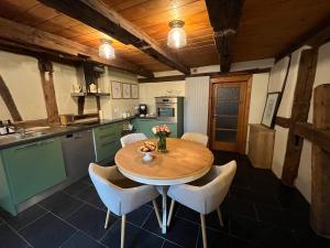 a kitchen with a wooden table and white chairs at Gîte aux charmes d'Antan in Weinbourg