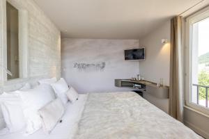 a bedroom with a bed with white pillows and a window at Les Loges Du Parc in Gérardmer