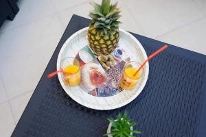 a plate with a pineapple and drinks on a table at Two apartments near the sea in Kaštela