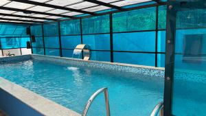 a large swimming pool with blue water in a building at Mayooram Back water Pool Villa in Kollam
