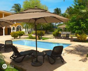 an umbrella and chairs next to a swimming pool at Hotel Hacienda de Izamal in Izamal