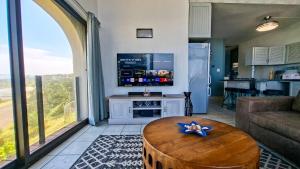a living room with a table and a tv at Uvongo Cabanas 13B in Uvongo Beach