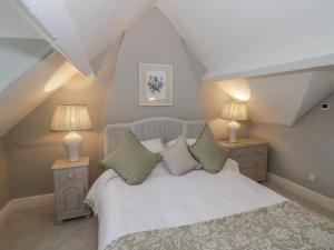 a bedroom with a bed with two night stands and two lamps at Bumblebee Cottage in Tetbury