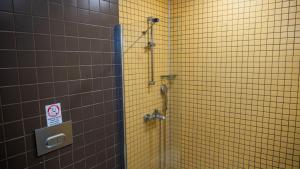 a shower in a bathroom with a yellow tiled wall at Otel Kefalos in Gokceada Town