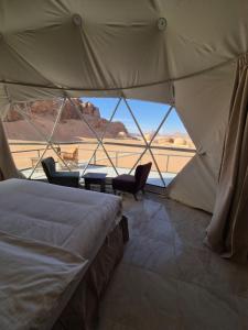 a bedroom with a bed and a view of the desert at Sofia Bubble Luxury Camp in Disah