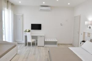 a white bedroom with a desk with a tv on the wall at Finestre sul Borgo in Cassano delle Murge