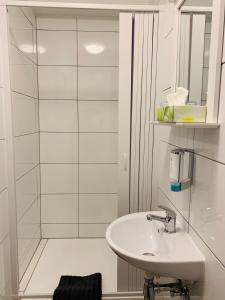 ein weißes Badezimmer mit Waschbecken und Dusche in der Unterkunft Checkinn Hotel in Bad Salzuflen