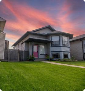 a house with a green lawn in front of it at Pink door-ed wonder in Grande Prairie