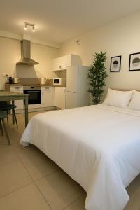 a bedroom with a large white bed and a kitchen at Les hébergements Rousseau in Oyonnax +14 photos