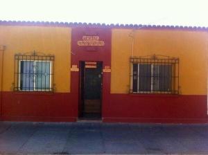 a red and yellow building with a door and windows at Andes Hostal Serena in La Serena