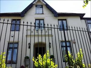 a white house with a black fence at Ruxley Rooms in Sidcup