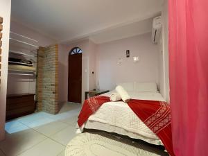 a bedroom with a bed with a red blanket at Hostel House Santinho in Florianópolis