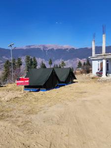 a tent in a field next to a building at Chanshal Camp in Khashdhār