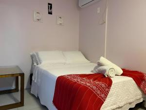 a bedroom with a bed with a red and white blanket at Hostel House Santinho in Florianópolis