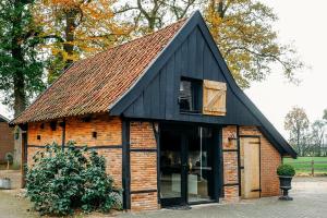 a small brick building with a black roof at Vakantiewoning Lemselermaten in Weerselo