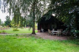 a pavilion with a table and chairs under a tree at Doppelzimmer Holthusen 25515 in Weener