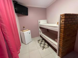 a small room with a small refrigerator and pink walls at Hostel House Santinho in Florianópolis