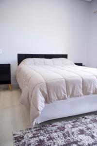 a bed with a white comforter on top of it at Flat2 Aconchegante com Cozinha Completa in Sinop