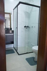 a bathroom with a glass shower with a toilet at Flat2 Aconchegante com Cozinha Completa in Sinop