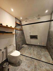 a bathroom with a toilet and a glass shower at Recanto do Guará Cabana in Capitólio +35 photos