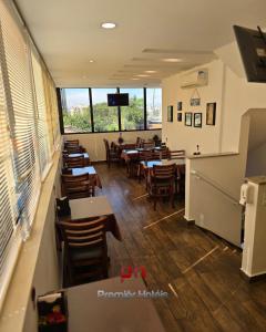 a dining room with tables and chairs and windows at Barueri Premiêr Hotel in Barueri