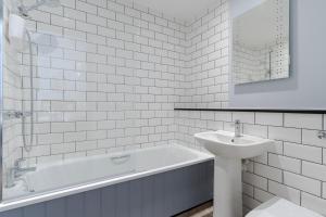 a white bathroom with a tub and a sink at Port Gaverne Hotel in Port Isaac