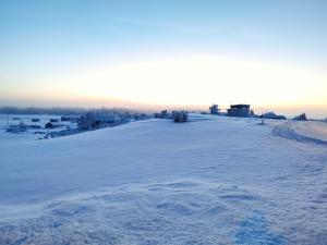 a snow covered hill with a house in the distance at Lumikko Aurora Loft in Enontekiö