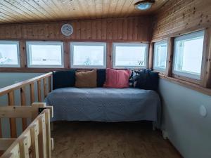 a couch in the corner of a room with windows at Lumikko Aurora Loft in Enontekiö