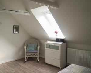 a attic room with a chair and a dresser and a window at Sommerliv Bed and Breakfast in Tranekær