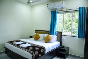 a bedroom with a bed with blue curtains and a window at Ganga Regency in Solapur