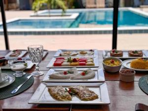 a table with several plates of food and a pool at Villa Manoá in São Miguel dos Milagres