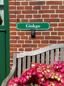 a green street sign next to a bench and flowers at Doppelzimmer Holthusen 25515 in Weener +10 photos