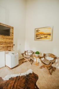 a living room with three chairs and a television at Pousada Fazenda Caetés in Camboriú