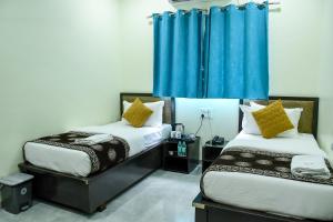two beds in a room with blue curtains at Ganga Regency in Solapur +17 photos