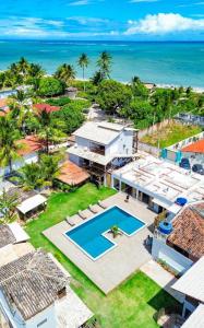 an aerial view of a house with a swimming pool and the ocean at Villa Manoá in São Miguel dos Milagres