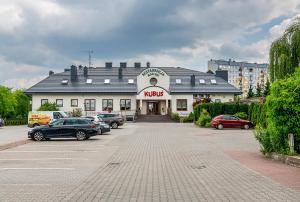 a large building with cars parked in a parking lot at Restauracja i Hotel KUBUŚ in Bełchatów