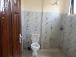 a bathroom with a toilet and a tiled wall at Modern Nest Studio Kikuyu in Rungiri